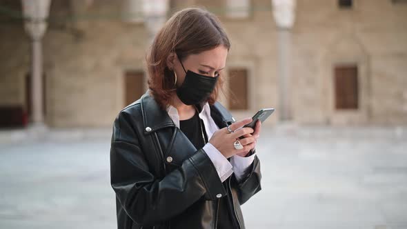 Concentrated Nervous Woman Wear Face Mask Check Coronavirus News with Her Mobile Phone Outdoors.