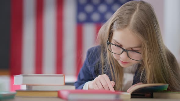 Absorbed Smart Teen Schoolgirl Reading Out Loud Sitting on the Right at Desk in Classroom with