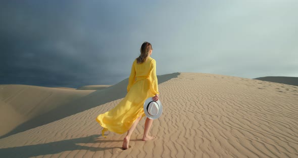 Cheerful Woman Walking on Top of Sand Dune in Desert