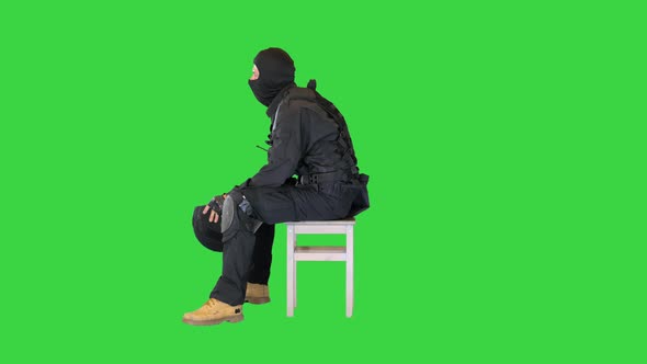 Riot Policeman Sitting with Helmet Off Having Rest on a Green Screen Chroma Key