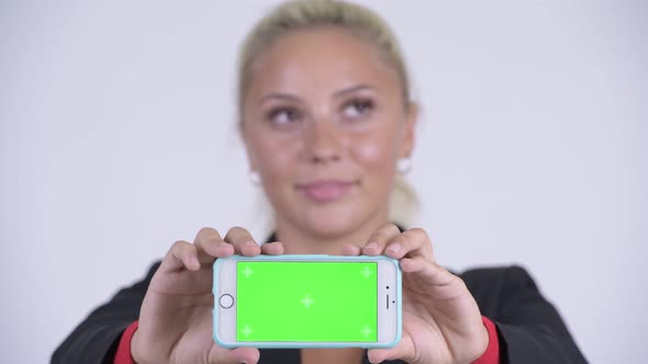 Face of Young Happy Blonde Businesswoman Thinking and Showing Phone