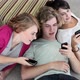 Three teenagers lying on floor looking at smartphones - VideoHive Item for Sale