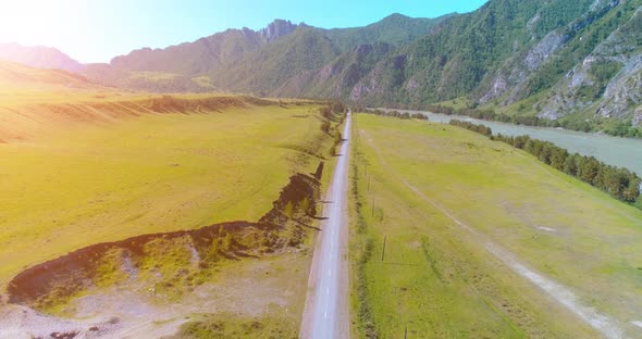 Aerial Rural Mountain Road and Meadow at Sunny Summer Morning. Asphalt Highway and River.