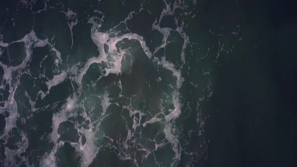 Aerial view of water rolling on beach from above