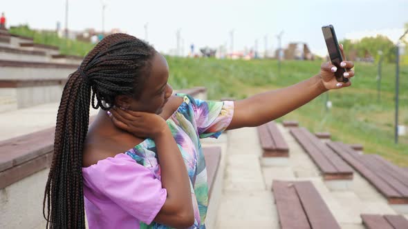 African-American Lady in Stylish Blouse Makes Selfie in Park