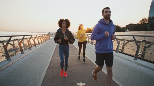 Diverse Friends Jogging Together in Morning Running on Workout Path at Seafront Slow Motion