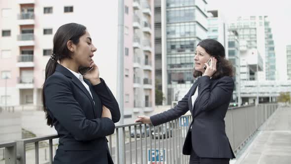 Businesswomen Talking By Smartphones on Street