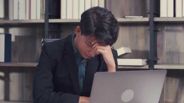 Stressed businessman feeling tired while sitting at his working place in the office.