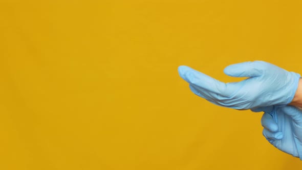 Close-up of female doctor's hands putting on blue sterile medical gloves
