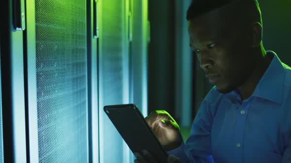 African american male computer technician using tablet working in business server room