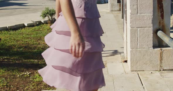 girl in pink dress and high-heeled shoes walks forward and spins around herself