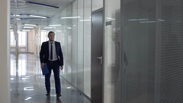 Businessman in Black Suit Walking Along Corridor
