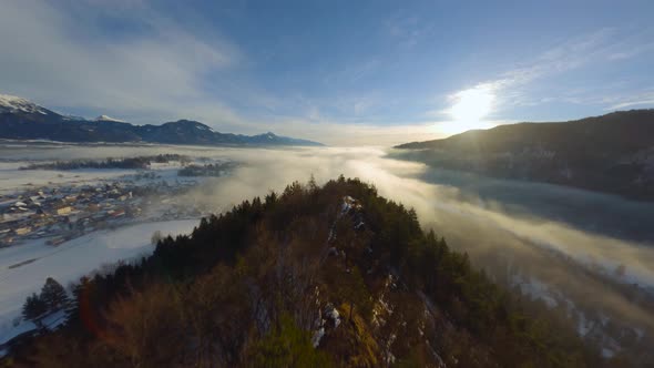 FPV Drone shot, the landscape covered under the fog with surrounding mountains in the morning at win