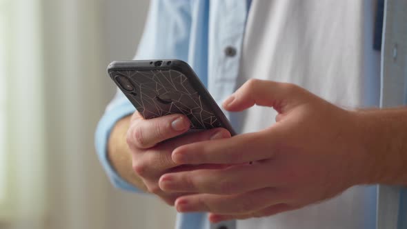 Close Up Young Man Holding Smartphone in Hands Scrolling News Feed Web Surfing Information Shopping