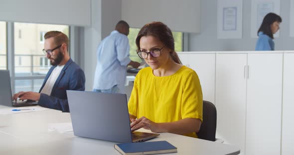 Caucasian Woman Working in Modern Office Holding Documents Using Computer