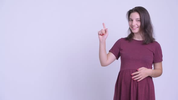 Happy Young Beautiful Pregnant Woman Thinking While Pointing Up