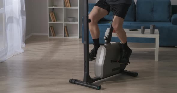 Sporty Man Is Spinning Pedals of Exercise Bike at Home Details View Training and Keeping His