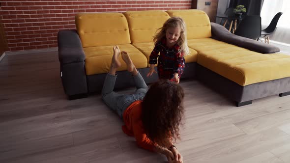 Little Girl Playing at Home with Mother and Climbing on Her Piggyback