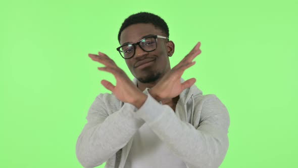 African Man Showing No Sign By Arm Gesture on Green Background