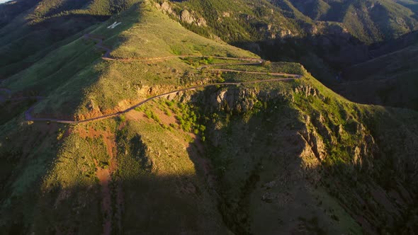 Aerial Shot Of Winding Road On Top Of Lush Mountainside During Gorgeous Golden Sunset Near Denver US