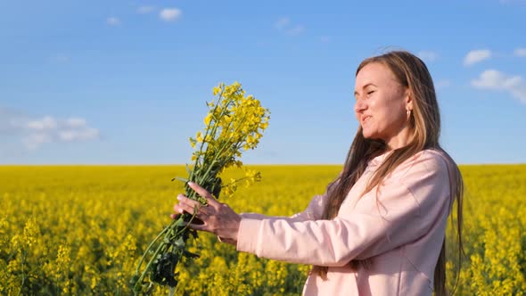 Happy Young Woman Admiring Enjoying a Yellow Bouquet of Rapeseed