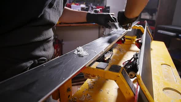Ski or Snowboard Tuning and Reapair Concept. Winter Shop Worker Doing Base Repair and Service
