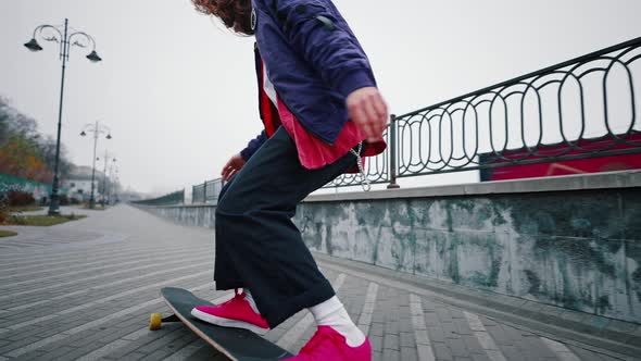 Longhaired Young Guy Demonstrating Tricks on a Longboard