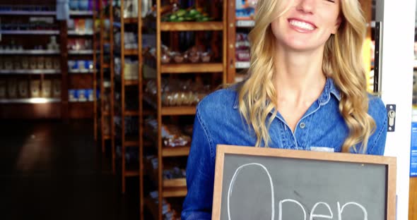 Smiling owner holding open signboard in supermarket