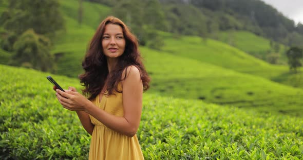 Traveler Woman With Smartphone During Her Travel on Famous Nature Landmark Tea Plantations in Sri