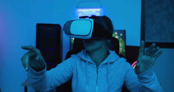 Girl gamer playing at 3D game online using virtual reality headset
