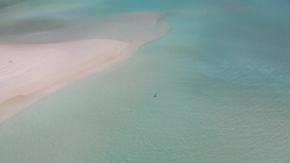A lonely vkula swims off the coast of the Maldivian island in turquoise water against the backdrop o