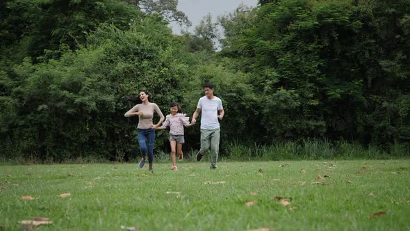 Slow motion of parents with daughter running enjoy in the park