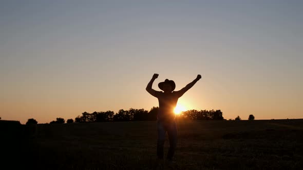 Happy Village Worker Dancing in a Field at Sunset