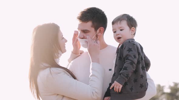 Young Lovely Woman and Man with a Son in Masks Are Kissing Outside