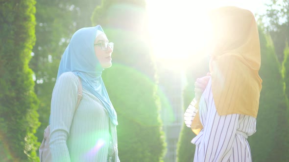 Two Young Hard of Hearing Muslim Women in Traditional Scarves and Glasses Communicate Using Sign