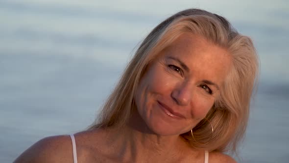 Extreme closeup of mature woman flirting with camera with ocean behind her.