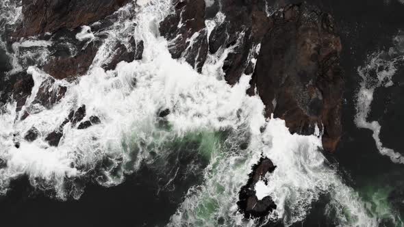 Ocean waves splashing on rocks from above