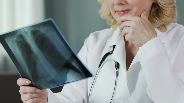 Professional Therapist Looking at Lung X-Ray and Smiling Into Camera, Closeup