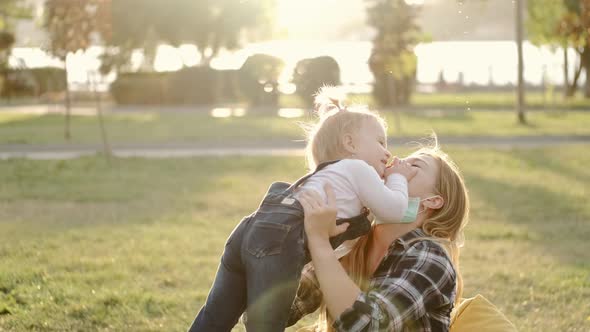 Mother and Little Daughter Are Having Fun in the Park in Sunny Weather