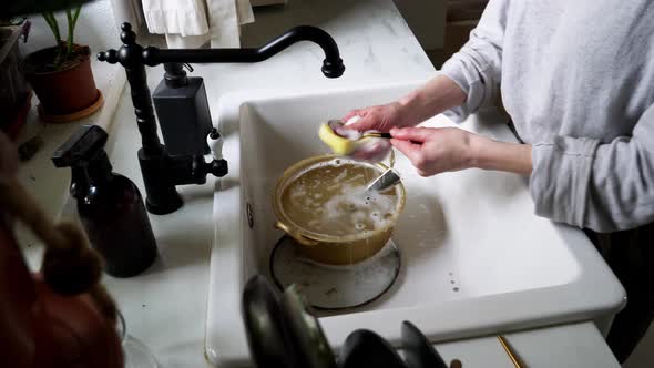 woman washes a pan in her kitchen
