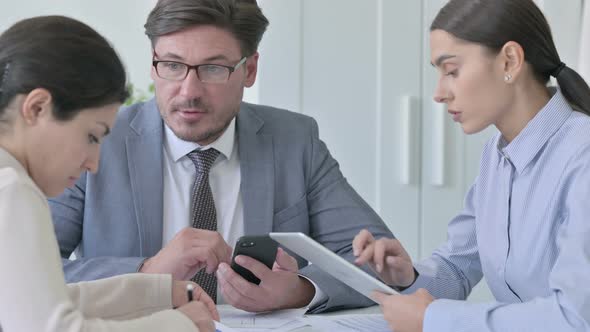 Serious Male and Female Business People having Discussion with Papers