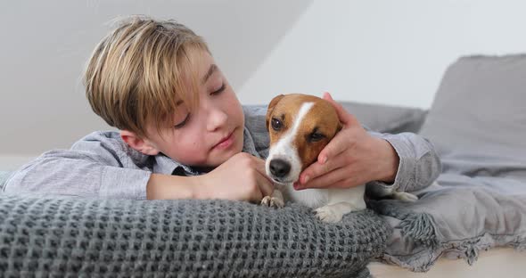 Boy cuddling his dog lying on bed