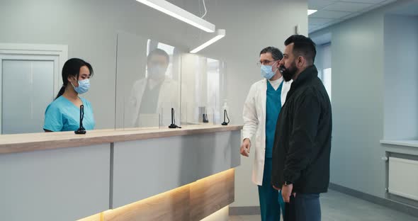 Bearded Patient Communicating with Doctor and Nurse on Reception