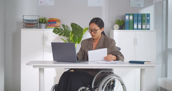 Young Pretty Disabled Woman in Wheelchair Working on Laptop Computer at Office