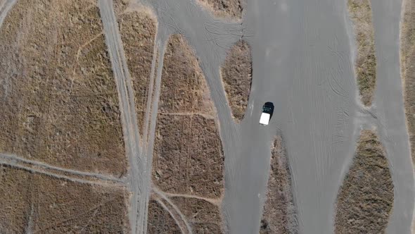 Cinematic overhead aerial view of off road car tour cruises on sea of sand desert.