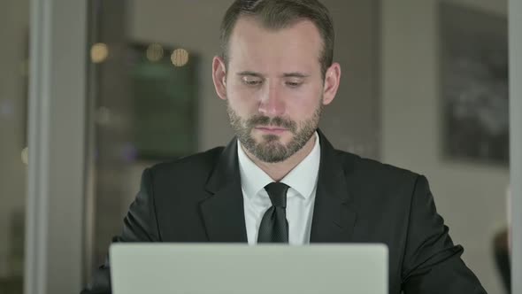 Close Up of Handsome Businessman Working on Laptop at Night