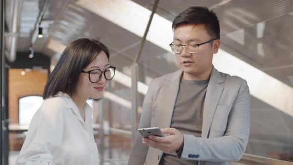 Two Asian Businesspeople Using Phone