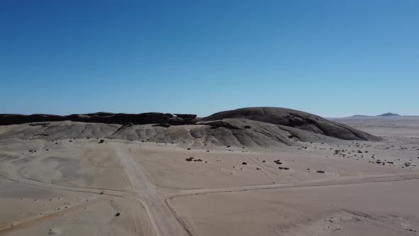 Drone footage of a person walking on a dusty road in a desert of Namibia