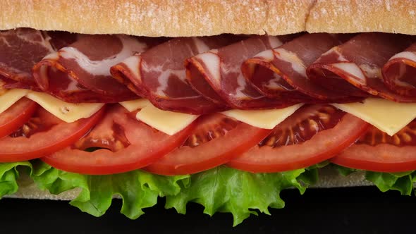 sandwich with ciabatta bread, ham, tomatoes, lettuce and cheese close up