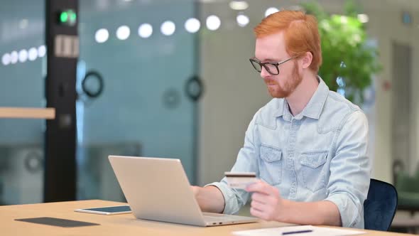 Online Payment Success on Laptop for Redhead Man in Office